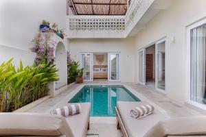 a pool in a house with white walls and ceilings at Mata Biru Villa by Betterplace in Uluwatu