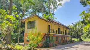 une maison jaune au milieu d'une route dans l'établissement Huaykhakhaeng Country Home Resort, à Ban Rai