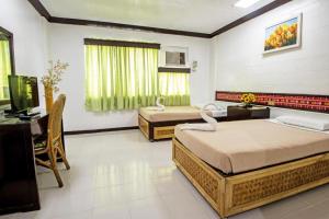 a bedroom with two beds and a desk and a television at Family Country Hotel and Convention Centre in Lagao +35 photos