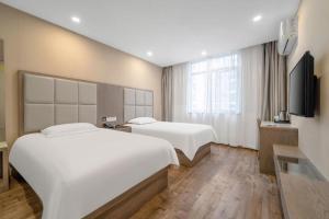 a hotel room with two beds and a flat screen tv at Jitai Hotel Shanghai Yangpu Benxi Hospital Branch in Shanghai