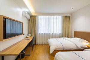 a hotel room with two beds and a desk and a television at GreenTree Inn Express Shanghai Baoshan District Youyi Road Metro Station in Baoshan +191 photos