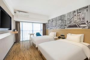 a hotel room with three beds and a tv at City Comfort Inn Yunfu Xinxing Juncheng Plaza in Yunfu +245 photos