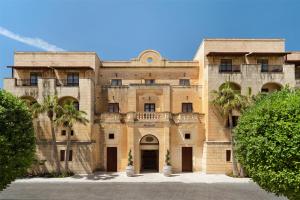 an old building with palm trees in front of it at Kempinski Hotel San Lawrenz in San Lawrenz