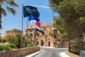 two flags flying in front of a building at Kempinski Hotel San Lawrenz in San Lawrenz