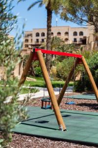 a swing set in a park with palm trees at Kempinski Hotel San Lawrenz in San Lawrenz