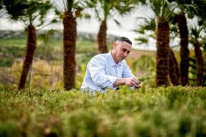 a man sitting in the grass with a plant at Kempinski Hotel San Lawrenz in San Lawrenz