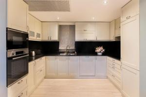 a white kitchen with white cabinets and black appliances at Kempinski Hotel San Lawrenz in San Lawrenz