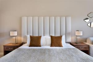 a bedroom with a large white bed with two lamps at Kempinski Hotel San Lawrenz in San Lawrenz