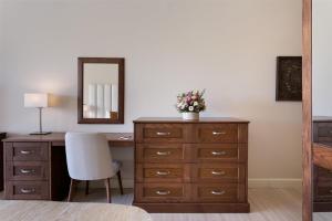 a bedroom with a dresser and a desk with a mirror at Kempinski Hotel San Lawrenz in San Lawrenz
