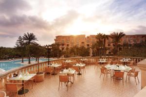 a restaurant with tables and chairs next to a pool at Kempinski Hotel San Lawrenz in San Lawrenz