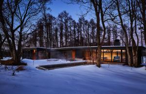 a glass house in the snow in the woods at SONEKA in Kitahiroshima