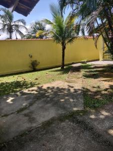 a yard with palm trees and a yellow wall at Casa com piscina em Bertioga in Bertioga