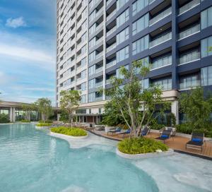 a swimming pool in front of a tall building at S Sriracha Hotel & Residence in Si Racha