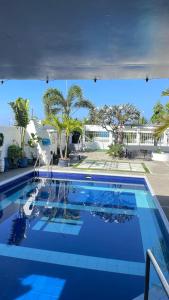 a blue swimming pool with palm trees in the background at The beach house, Baroro in Bacnotan