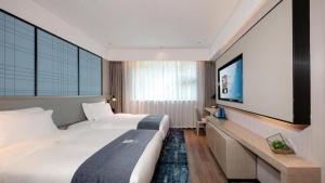 a bedroom with a large bed and a flat screen tv at Echarm Hotel Chengdu Happy Valley Southwest Jiaotong University in Chengdu