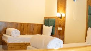 a bedroom with two beds and a wooden wall at Monal Homestay in Kulu