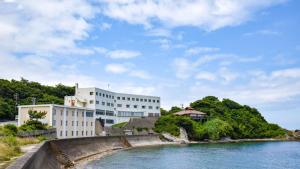 浜田市Marine Hotel Harimo的水域旁边的一座白色大楼