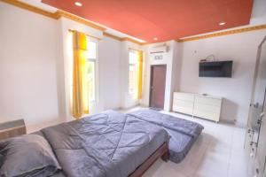 a bedroom with a large bed and a television at Hotel Mega Dana in Kesiman