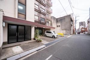 Un coche blanco aparcado delante de un edificio en GoodStay401, en Kurume