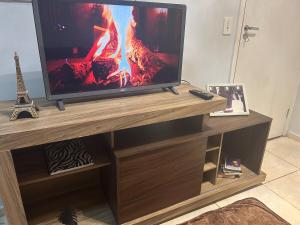 TV de pantalla plana en la parte superior de un centro de entretenimiento de madera en Apartamento Lirio Confort, en Franca