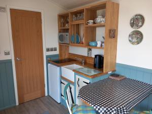 a small kitchen with a table and a door at The Mad Hatter's Shepherd's Hut in Carlisle