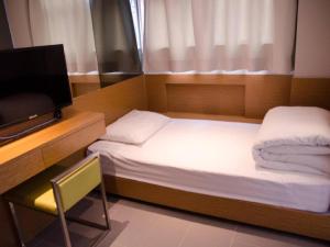 a small bedroom with two beds and a television at Acesite Knutsford Hotel in Hong Kong +63 photos