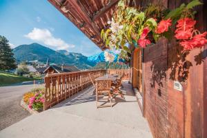 a table and chairs on a balcony with flowers at Appartement spacieux à Châtel 120 m² avec terrasse privée in Châtel