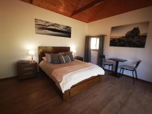 Un dormitorio con una cama y una mesa y una ventana. en Rostrevor Pickers Cottage, en Triabunna