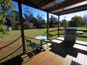 porche con mesa, sillas y parrilla en Rostrevor Pickers Cottage, en Triabunna