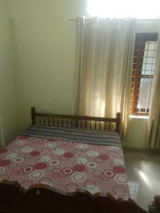 a bedroom with a bed with a quilt and a window at Home stay in Varkala