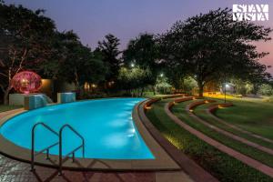 a swimming pool in a park at night at Nivaant Farms by StayVista - Green Retreat with Pool, Orchard, Jacuzzi & Gazebo in Karjat