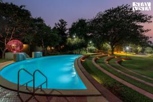 ein Schwimmbad in einem Park in der Nacht in der Unterkunft Nivaant Farms & Cottages - Nestled in lush greenery, offering a Swimming pool, Orchard, Jacuzzi & A spacious lawn with gazebo in Karjat