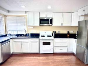 Una cocina con gabinetes blancos y un refrigerador de acero inoxidable. en Allura Encantado - Temecula Wine Retreat, en Temecula
