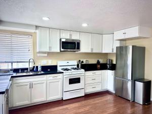 Una cocina con gabinetes blancos y un refrigerador de acero inoxidable. en Allura Encantado - Temecula Wine Retreat, en Temecula