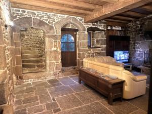 ein Wohnzimmer mit einer Couch und einem Fernseher in einer Steinmauer in der Unterkunft Splendide MANOIR - Proche plages - 4 chambres - 3sdb - 8 pers - WIFI in Plounérin