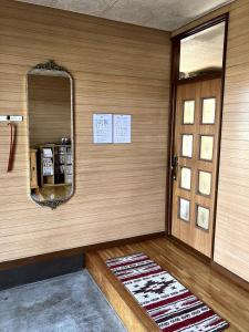 a room with a door and a mirror and a rug at KeNJIRO HOUSE in Oshirabetsu