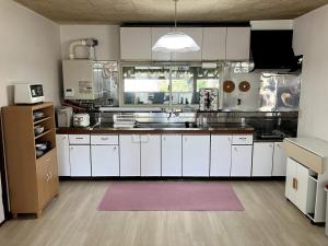 a large kitchen with white cabinets and a pink rug at KeNJIRO HOUSE in Oshirabetsu