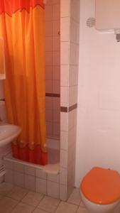 a bathroom with a orange shower curtain and a toilet at Judit Apartmanok in Budapest