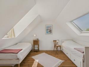 a attic bedroom with two beds and a chair at Maison avec jardin pour 4 adultes et 2 enfants in Beg-Meil