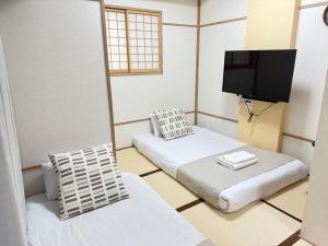 a room with two beds and a flat screen tv at Apartment Hotel Side of Shinsaibashi Shopping street in Osaka