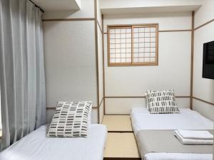 two beds in a room with a window at Apartment Hotel Side of Shinsaibashi Shopping street in Osaka
