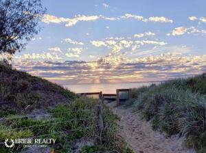 a sandy path leading to a beach with a sunset at Above The Dunes in Woorim