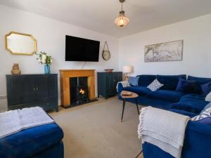 a living room with blue couches and a fire place at Ael Y Fron in Pwllheli
