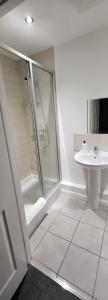 Un baño blanco con ducha y lavabo. en 4 Bedroom Home Tameside Greater Manchester Sleeps 8, en Mánchester
