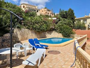 a swimming pool with chairs and a table and a table and chairs at Villa June in Benitachell