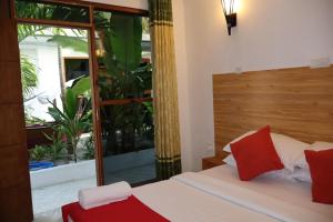 a bedroom with a bed with red pillows and a window at Dhontakuru Guest House in Ariyaddu