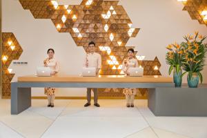 three women standing at a table with laptops at TMS Hotel Da Nang Beach in Da Nang