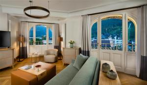 a living room with a couch and a large window at Kempinski Palace Engelberg in Engelberg