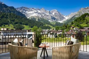 a balcony with two chairs and a table and mountains at Kempinski Palace Engelberg in Engelberg