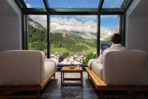 a person sitting on a couch looking out of a window at Kempinski Palace Engelberg in Engelberg +128 photos